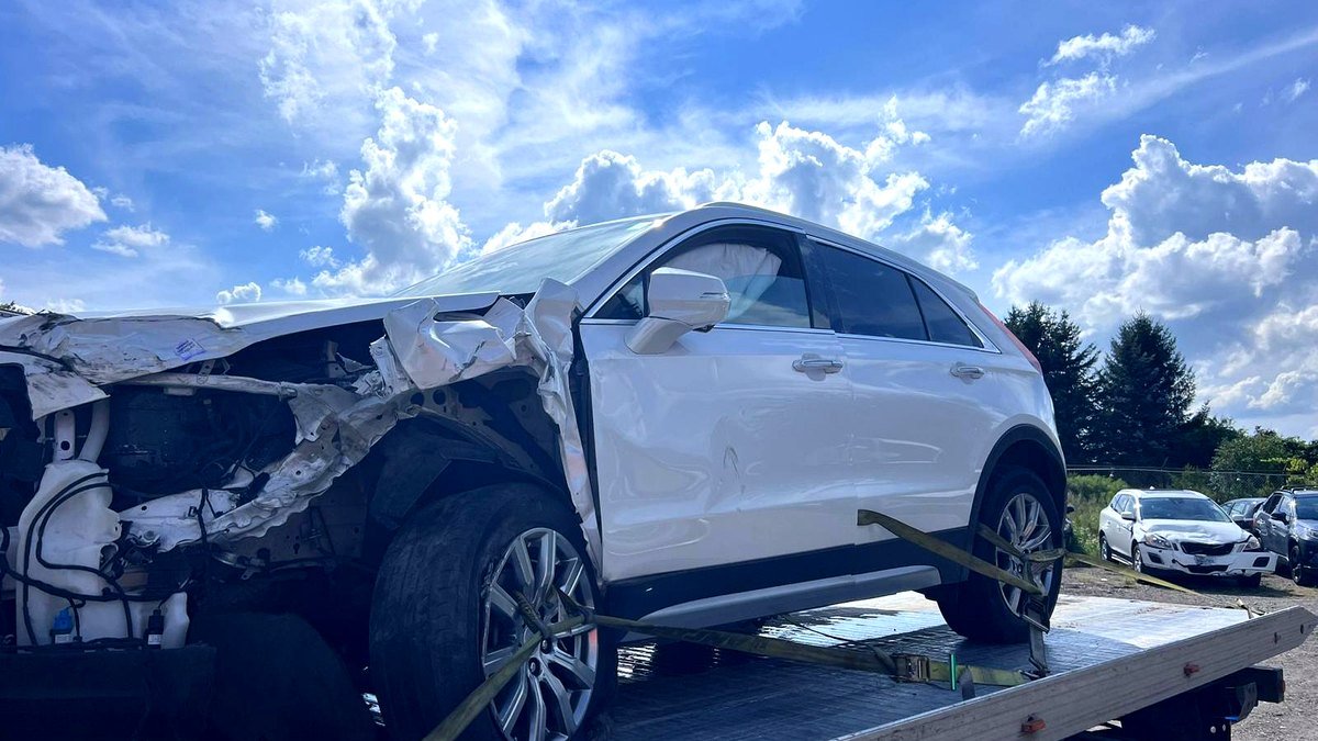 Collision-damaged Cadillac XT4 strapped on the flatbed during a scrap car removal in London, Ontario